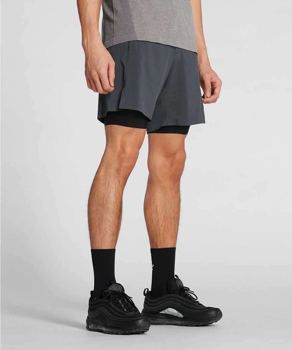 Woman wearing a gray athletic outfit with black shorts on a light gray background RYU