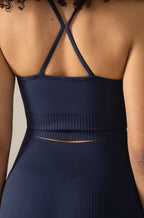 Navy blue athletic outfit with criss-cross straps on a neutral background