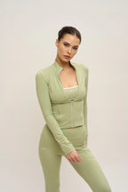 Woman wearing a green athletic outfit on a plain background