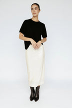 Women wearing a black top and white skirt on a plain background Amanda Maria