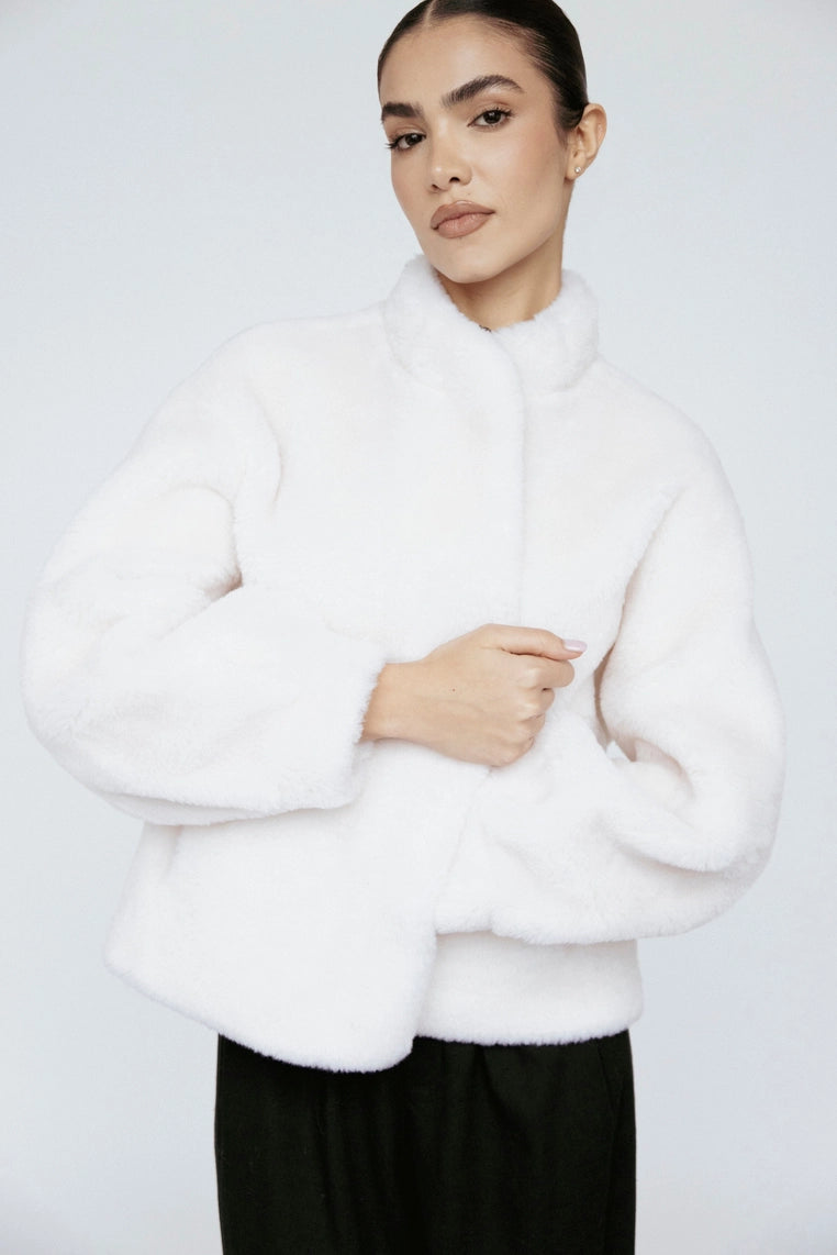 Woman wearing a white fluffy sweater against a plain background
