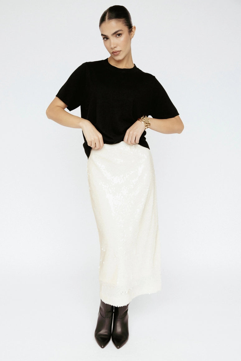 Woman wearing a black t-shirt and white skirt on a white background Amanda Maria