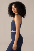 Woman wearing a navy blue athletic outfit on a beige background