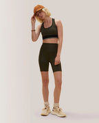 Women wearing a black sports bra and shorts set with a brown cap on a light gray background Rose Boreal