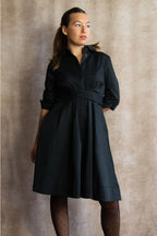 Woman wearing a black dress against a beige background ANNICK