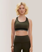 Woman wearing an olive green sports bra and leggings on a plain background Rose Boreal