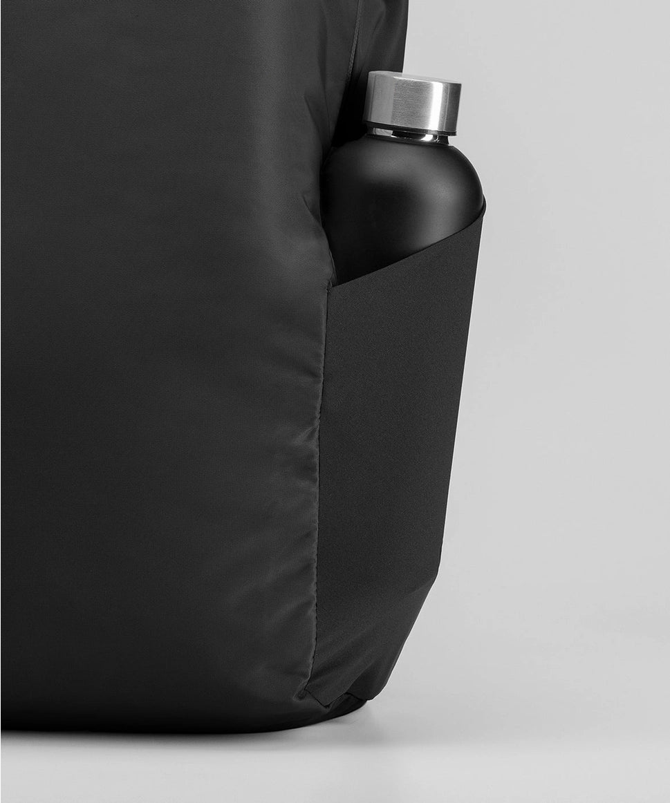 Black backpack with a water bottle in a pocket on a light gray background RYU