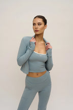 Woman wearing a light blue athletic outfit on a plain background