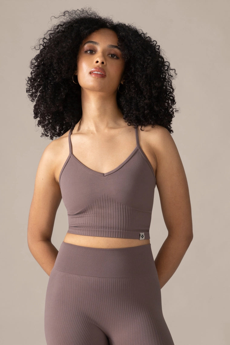 Woman wearing a brown sports bra and leggings set against a neutral background