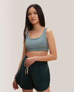 Woman in Rose Boreal grey athletic wear and cap standing outdoors with white in the background