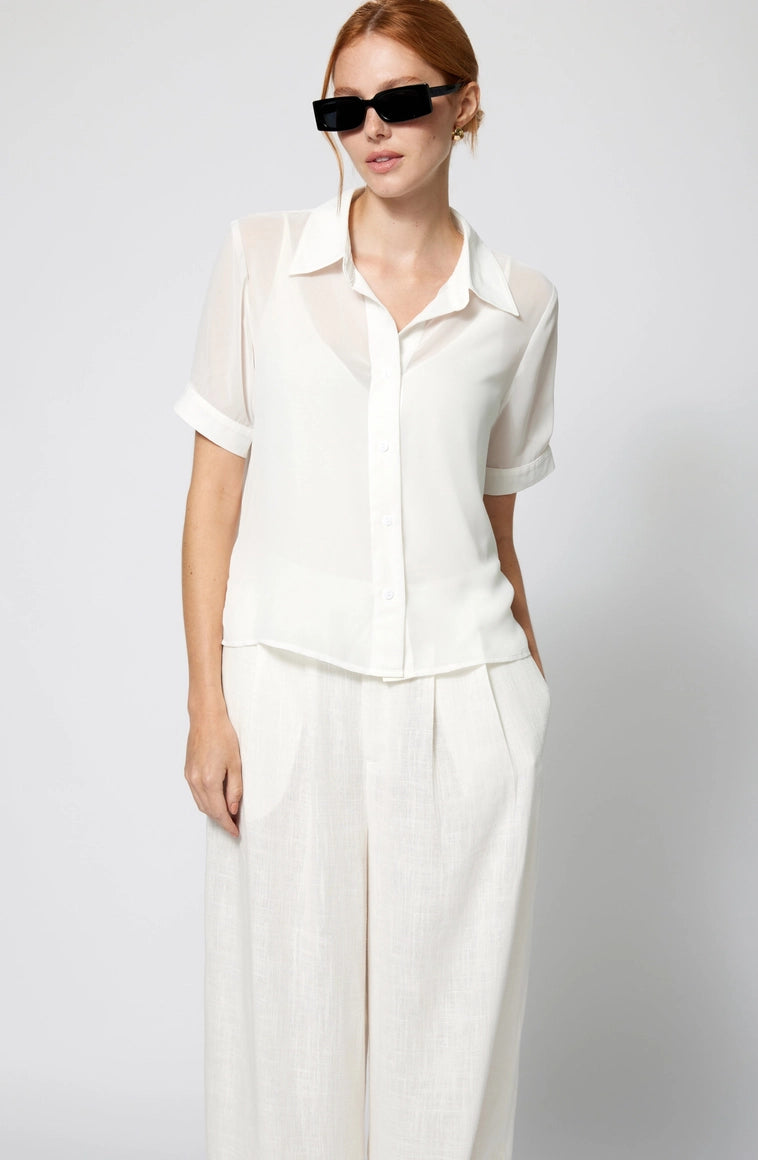 Woman wearing a white outfit with sunglasses on a plain background Amanda Maria