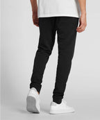 Man wearing black jogger pants and white sneakers on a plain background RYU