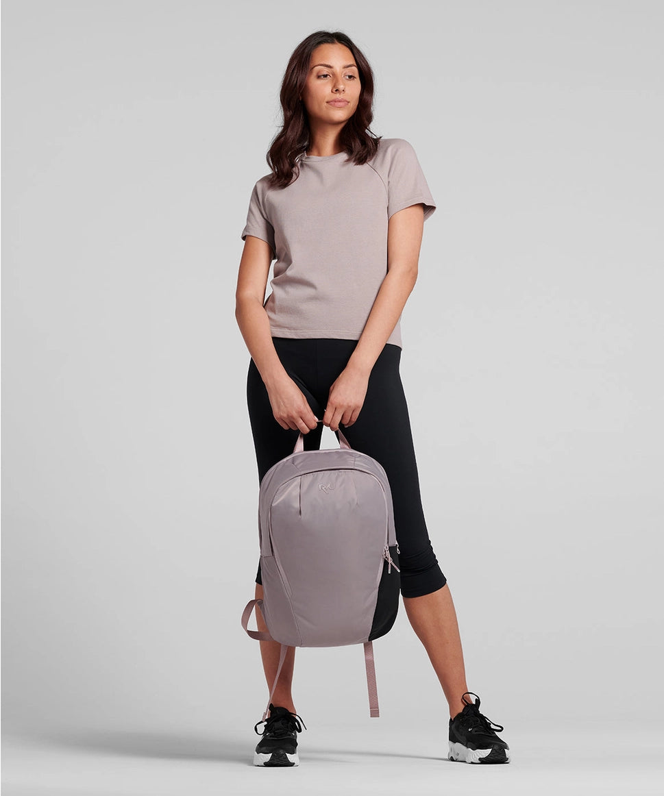 Woman holding a gray backpack against a plain background RYU