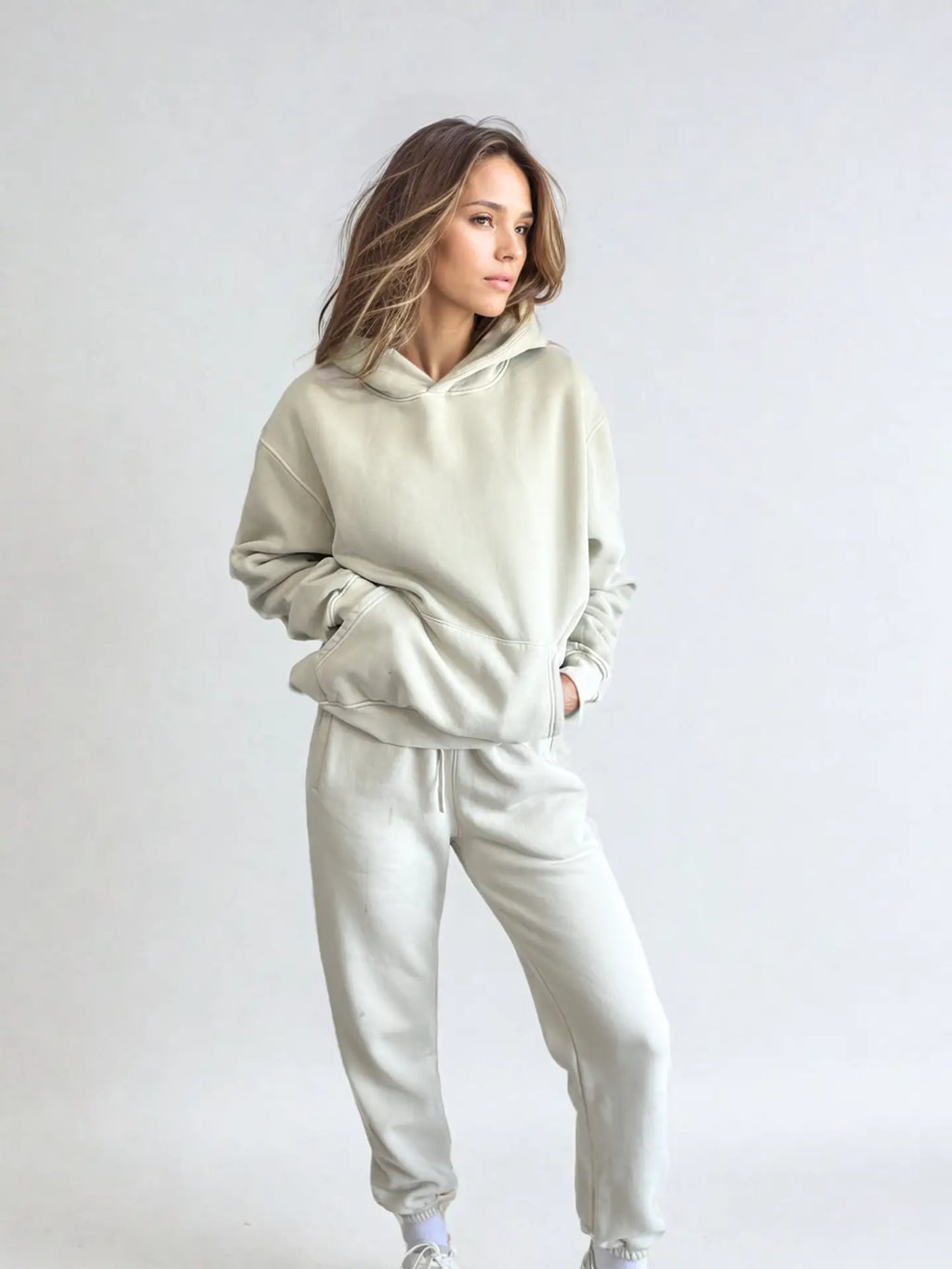 Woman wearing a light gray tracksuit against a white background PRIV