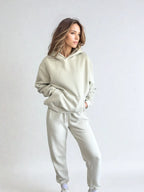 Woman wearing a light gray tracksuit against a white background PRIV