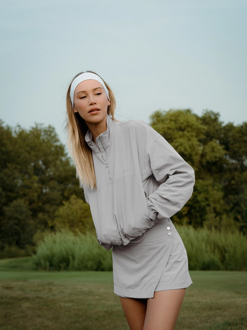 Woman in a light BOV skirt gray outfit standing outdoors with greenery in the background