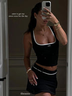 Woman taking a mirror selfie wearing a black tank top and skirt with text overlay.