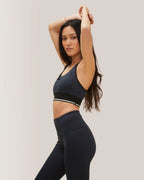 Woman wearing a black sports bra and leggings against a plain background Rose Boreal