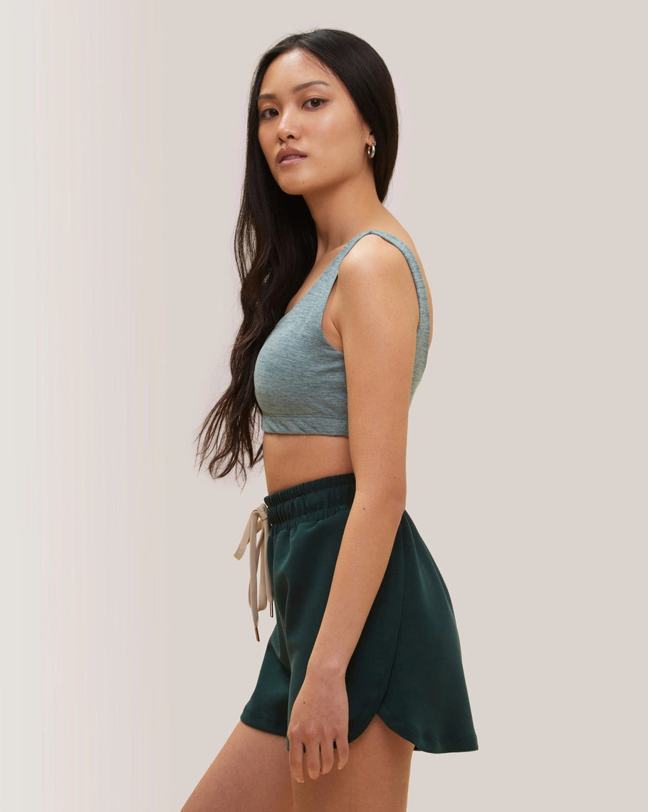 Woman in Rose Boreal floral athletic wear and cap standing outdoors with white in the background