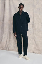 Man wearing a dark suit with white shoes against a neutral background Devlyn van Loon  