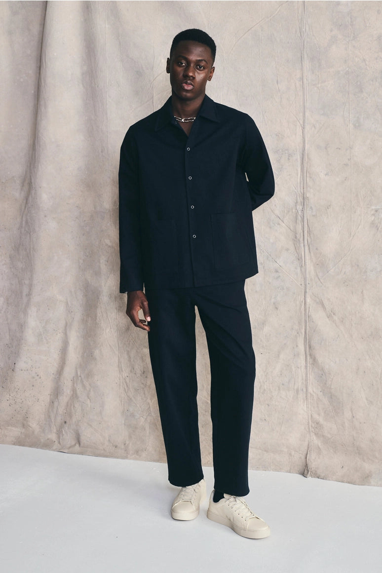 Man wearing a dark suit with white shoes against a neutral background Devlyn van Loon  