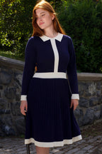 Woman wearing Clarissa knit dress in navy with white contrast trim, full body shot
