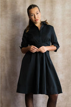 Woman wearing a black dress against a neutral background ANNICK