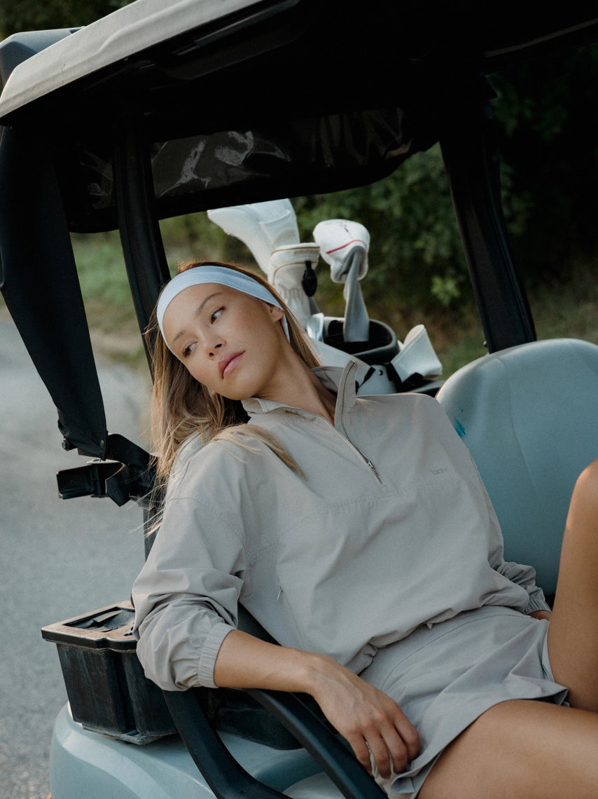 Woman sitting in a golf cart on a road with a scenic background in a grey BOV skirt